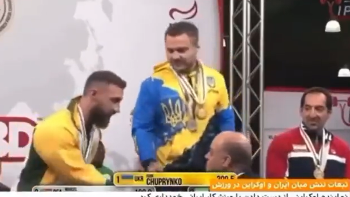 Активист приветствует украинского спортсмена, который отказался пожать руку иранским участникам