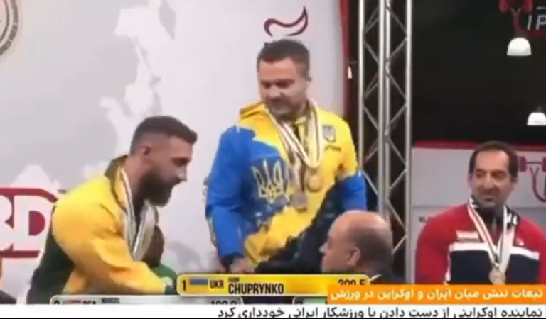 Активист приветствует украинского спортсмена, который отказался пожать руку иранским участникам